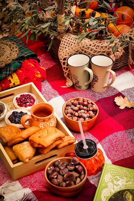 A red colored gingham blanket/cloth is laid out with various pastries, nuts, and fall décor. Two mugs sit off to the side. 