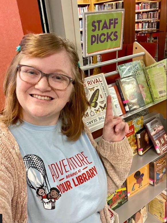 Abby of Youth Services in front of the YS staff picks shelf.